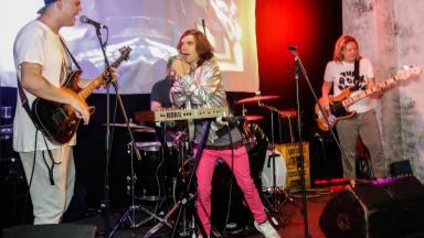 Three people in a band performing on stage